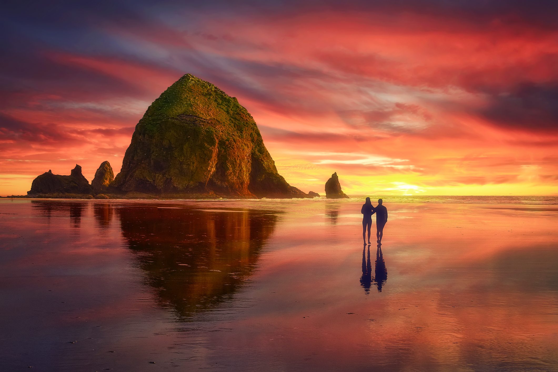 Dramatic clouds caressing Haystack Rock at sunset on Cannon Beach, Oregon