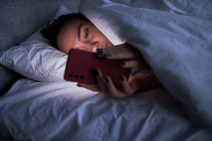 Calm woman using cellphone in bed