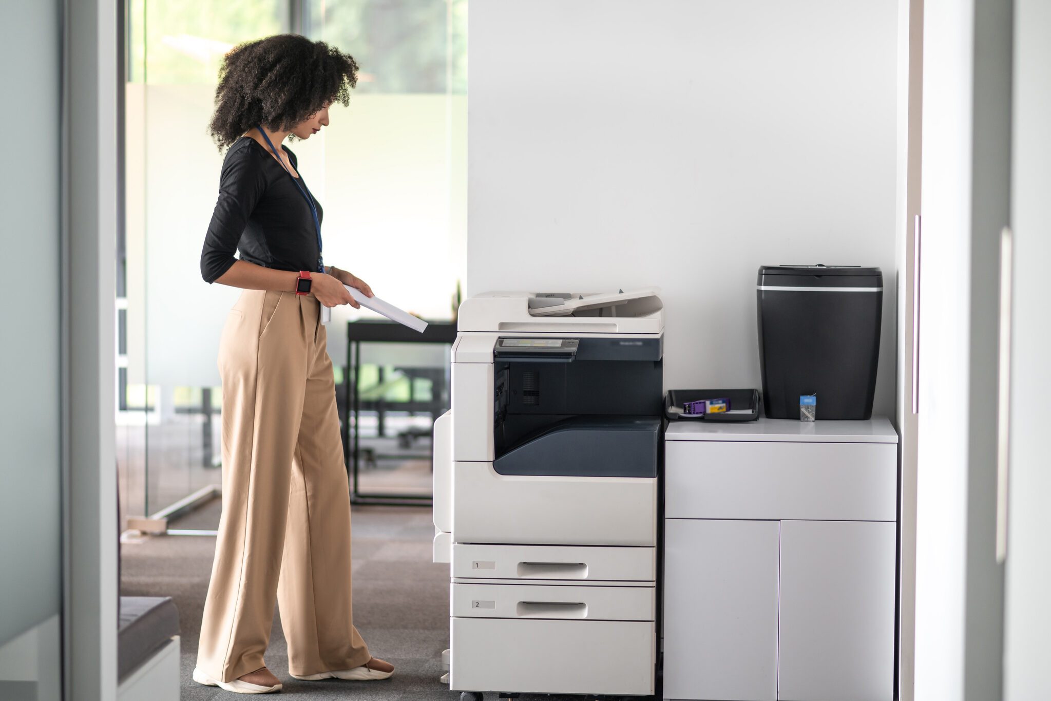 Woman in balck shirt and beige pants in the office looking determined