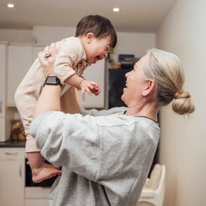 Grandmother holds smiling grandson in the air