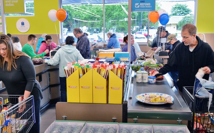 Customers shop at an Aldi supermarket during its grand opening, balloons in background