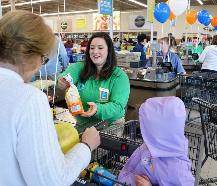 Aldi worker helps a customer check out with their groceries