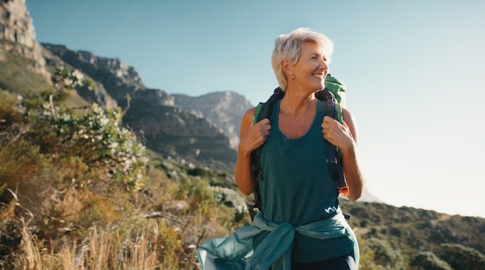 Senior woman carrying a backpack and hiking in rugged mountains