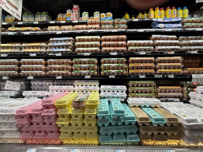 Egg cartons stacked and on display in refrigerated aisle a grocery store