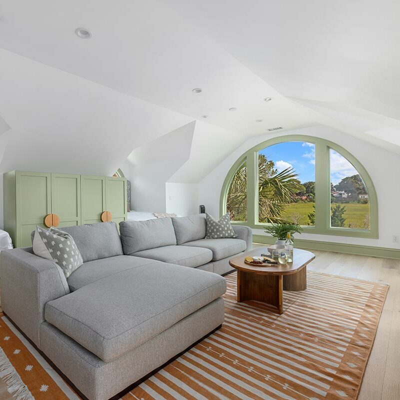 Bedroom with couch and vaulted ceilings and a half-moon window