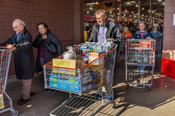 People with shopping carts filled with groceries walking out of Costco store
